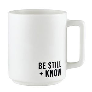 May include: White ceramic mug with a square handle. The mug features the text "BE STILL + KNOW" in black, centered on the front. The mug has a simple, modern design, suitable for coffee or tea.