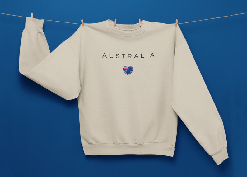 May include: A beige sweatshirt with the word "AUSTRALIA" printed on the front, and a small heart with the Australian flag inside.