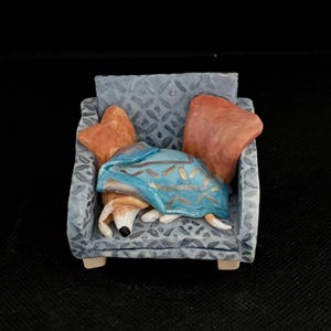 Porcelain whippet, greyhound, sight hound lurcher podenco galgo sculpture ornament, model, pottery dog, unique, handmade on an armchair.