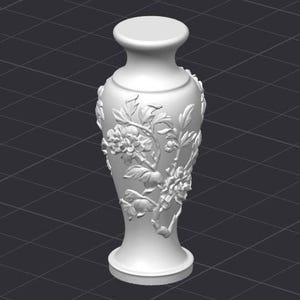 May include: A white ceramic vase with a floral relief design. The vase features a wide base, a slender neck, and a rounded top. The floral pattern includes detailed flowers and leaves, adding a decorative element to the vase.