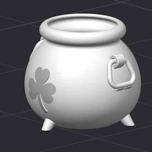May include: A white ceramic pot with a shamrock design and a handle. The pot has three legs and is shaped like a cauldron.