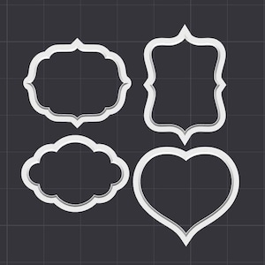 May include: Four white cookie cutters, one heart shaped, one cloud shaped, and two rectangular with rounded corners.