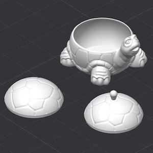 May include: A white ceramic turtle shaped container with a removable lid. The turtle has a detailed shell and a smooth, rounded body. The lid is also shaped like a turtle shell.