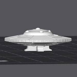 Könnte beinhalten: Ein weißes Modell einer fliegenden Untertasse mit einem runden Oberteil und einem flachen Boden. Die Untertasse hat eine Reihe kleiner Fenster am Rand des Oberteils.