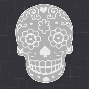 May include: A white sugar skull with intricate floral designs, a heart, and a spade symbol. The skull has a toothy grin and is decorated with small stars.