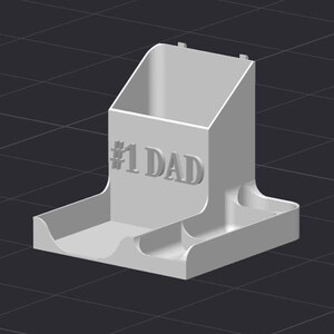 May include: A light gray desk organizer with the text "#1 DAD" embossed on the front. The organizer has a compartment for pens and pencils, and two smaller compartments on the base. The design is a 3D render.