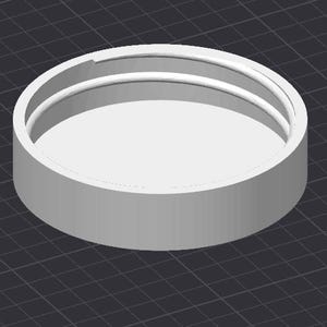 Peut inclure: Objet cylindrique blanc, rendu en 3D, avec un intérieur en retrait et deux anneaux concentriques. L'objet est posé sur un fond sombre à motif quadrillé, suggérant une conception ou un modèle numérique.