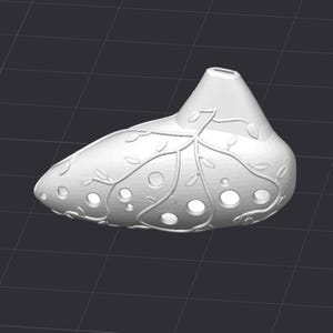 May include: A white ocarina with a leaf and vine design. The instrument has several circular holes and a mouthpiece. The surface is smooth, and the design is raised, creating a textured appearance. The ocarina is a musical instrument.