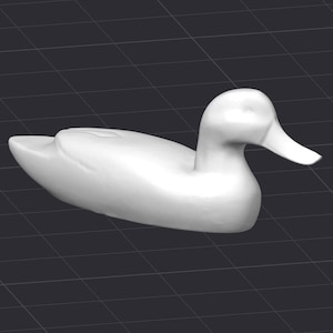 Puede incluir: Figurita de pato de cerámica blanca con un cuerpo liso y redondeado y un pico largo y delgado. El pato está acostado de lado con la cabeza girada hacia la derecha.