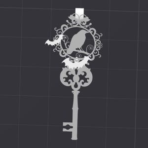Op de afbeelding: Zilverkleurig sleutelvormig ornament met een raaf in een decoratief cirkelvormig frame, met vleermuismotieven. De sleutel heeft een gotisch ontwerp, ideaal voor Halloween of gothic decoraties.