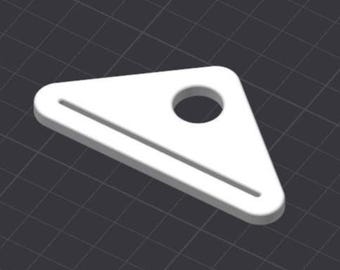 May include: A white, triangular object with a circular hole and a linear groove. The object is set against a dark gray, grid-patterned background. The design is simple and geometric.