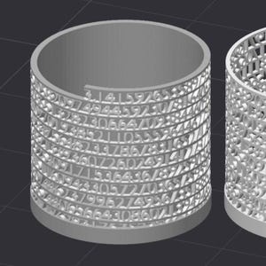 Op de afbeelding: Een lichtgrijs cilindrisch object met de cijfers van Pi uit de zijkanten gesneden. De cijfers zijn in rijen en kolommen rond de cilinder gerangschikt. De bovenkant van de cilinder is open en de onderkant is een massieve basis.
