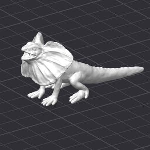 Peut inclure: Une figurine en plastique blanche d'un lézard à collerette avec une grande collerette autour du cou. Le lézard est debout sur une surface gris foncé.