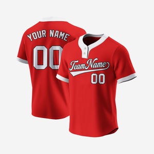 May include: Red baseball jersey with white trim and a white number "00" on the back. The front of the jersey has a white collar with a button and the text "Team Name" in white with a white number "00" underneath.