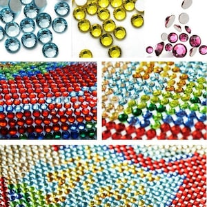 May include: Close-up of colorful round rhinestones, some in a loose pile and others arranged in a grid pattern. The rhinestones are various shades of blue, green, red, yellow, and clear.