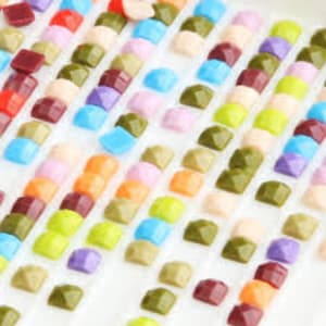 May include: Close-up of a tray of colorful diamond painting drills, arranged in rows. The drills are small, square, and have a variety of colors, including red, orange, yellow, green, blue, purple, and pink.