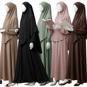 May include: Five mannequins wearing long-sleeved, floor-length dresses with matching head coverings in beige, black, sage green, dusty rose, and dark brown. The dresses feature a layered bodice design, gathered cuffs, and a textured fabric finish.