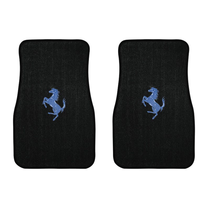 Pu&ograve; includere: Due tappetini neri per auto con un logo blu di un cavallo rampante. I tappetini sono rettangolari con la parte superiore curva e presentano una superficie strutturata. Il logo &egrave; centrato su ogni tappetino.