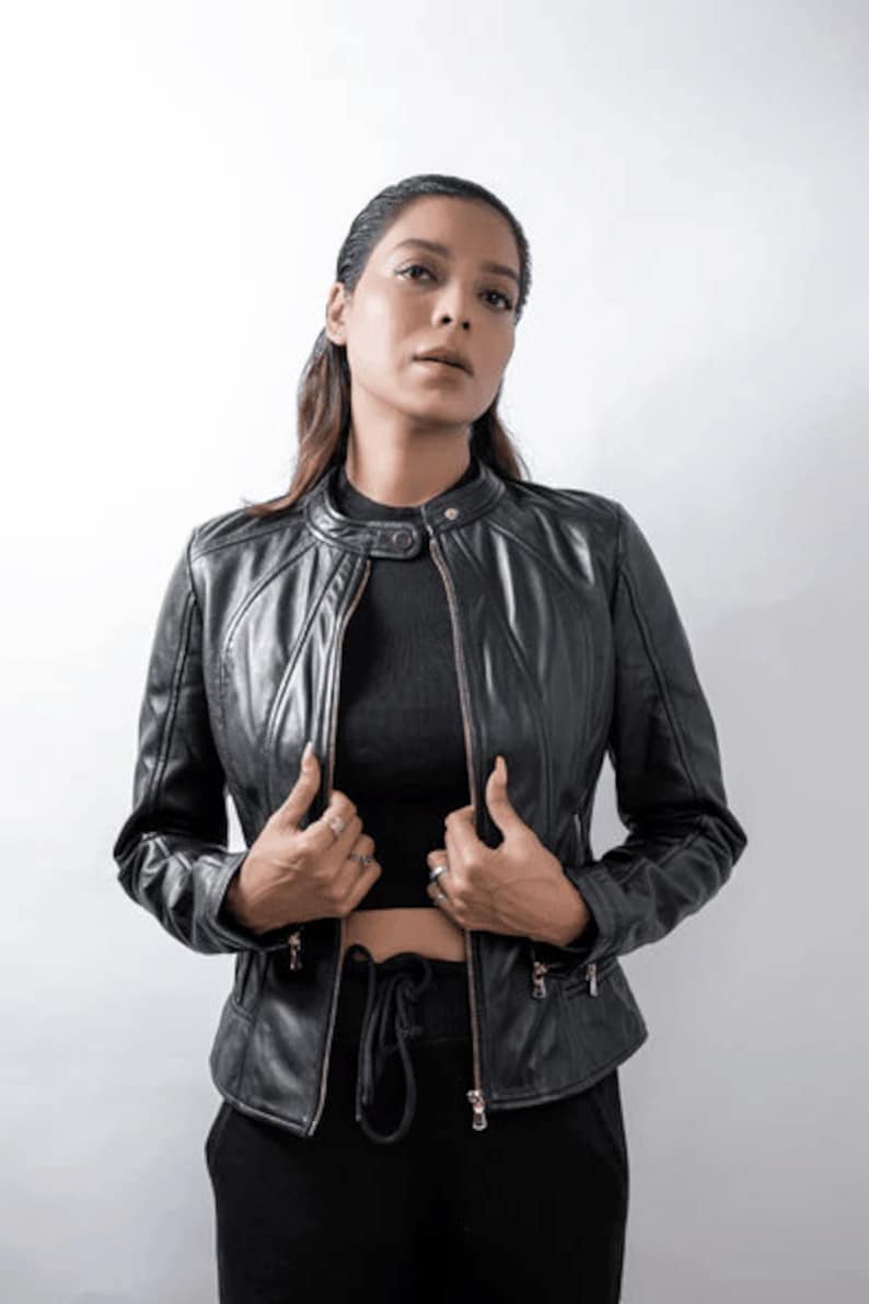 Peut inclure: Une femme portant une veste en cuir noire avec une fermeture &eacute;clair. Elle porte un haut noir et un pantalon noir.