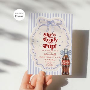以下が含まれることがあります： ヴィンテージデザインのベビーシャワーの招待状。招待状には、赤い文字で「She's Ready to Pop!」と書かれており、コカ・コーラのボトルの絵が描かれています。背景は青と白のストライプです。