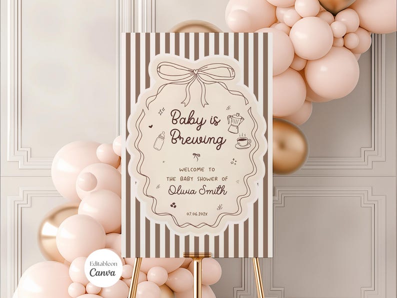 K&ouml;nnte beinhalten: Ein Babyparty-Schild mit dem Text "Baby is Brewing" in einem dekorativen Rahmen. Das Schild steht auf einer goldenen Staffelei, mit gestreiftem Hintergrund. Ballons in Rosa- und Goldt&ouml;nen sind im Hintergrund.
