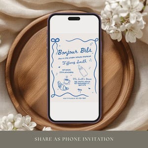 May include: A blue and white phone screen displaying a baby shower invitation with the text "Bonjour Bebe" and "Tiffany Smith". The invitation includes a baby bottle, a croissant, and a cup of coffee.