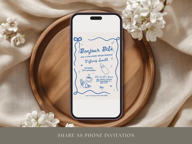 May include: A blue and white phone screen displaying a baby shower invitation with the text "Bonjour Bebe" and "Tiffany Smith". The invitation includes a baby bottle, a croissant, and a cup of coffee.