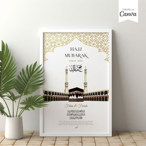 Puede incluir: Impresi&oacute;n art&iacute;stica enmarcada en blanco con dise&ntilde;o geom&eacute;trico dorado y caligraf&iacute;a &aacute;rabe. La impresi&oacute;n presenta una ilustraci&oacute;n de la Kaaba y dos minaretes, con las palabras "Hajj Mubarak" y la fecha 1445/11/2024. Un jarr&oacute;n blanco con hojas verdes est&aacute; en primer plano.