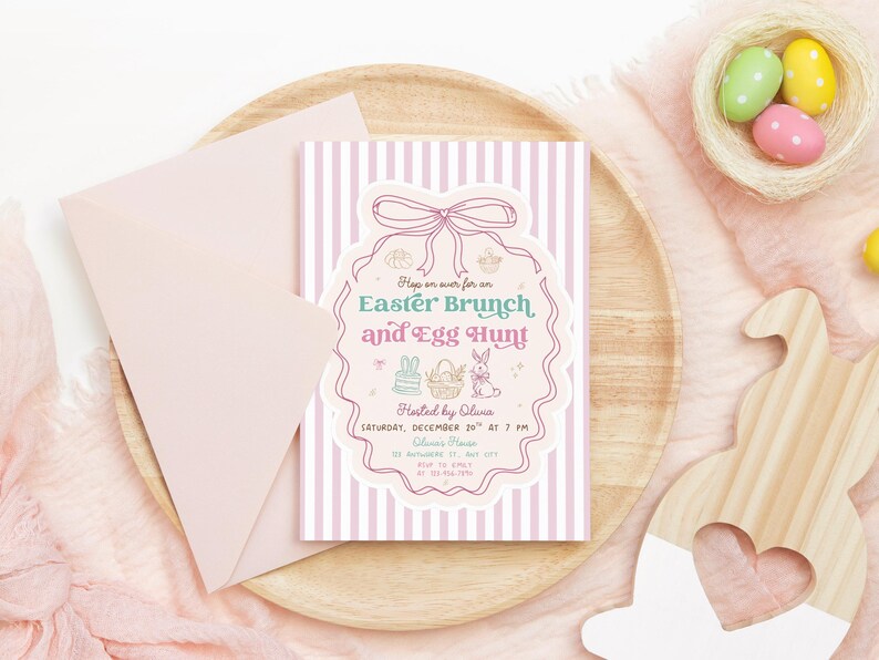 Puede incluir: Una invitaci&oacute;n a un brunch de Pascua y una b&uacute;squeda de huevos con rayas rosas y blancas, un sobre rosa y una bandeja de madera. La invitaci&oacute;n presenta un borde decorativo y texto. Tambi&eacute;n hay un nido con huevos de colores y un conejito de madera.