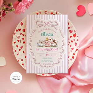 Könnte beinhalten: Eine rechteckige Geburtstagseinladungskarte mit hellvioletten vertikalen Streifen und einem mittigen, gewellten Rahmen mit Schleifenillustration. Die Karte zeigt Zeichentricktiere, den Text Olivia is turning One! sowie Veranstaltungsdetails.