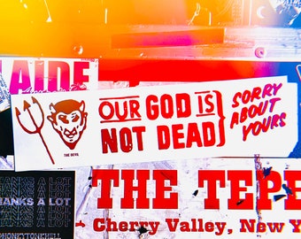 May include: A collection of colorful stickers with various messages, including "Our God is Not Dead" and "The Tepei Cherry Valley, New York". The stickers are on a textured surface with a yellow, pink, and blue background.