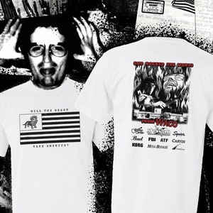 Può includere: Maglietta bianca con una grafica di bandiera americana in bianco e nero con un leone e il testo "Will the Beast Take America?" sul davanti e una grafica in bianco e nero di un uomo che suona una tastiera con fiamme e il testo "God Rocked the World From Waco" sul retro.