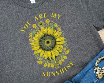 May include: A dark gray t-shirt with a yellow sunflower graphic and the text "You are my sunshine".