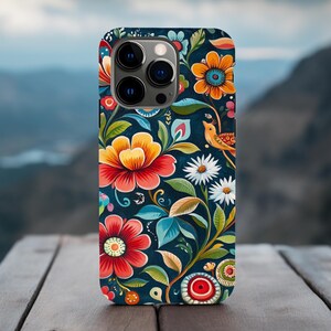 May include: A phone case with a colorful floral pattern. The case features a dark blue background with bright red, yellow, and green flowers. A small bird is perched on a branch in the upper right corner of the case.