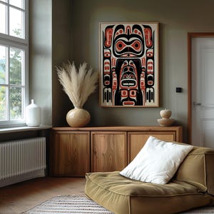 May include: A wooden cabinet with two doors and a white cushion on a brown floor. A large framed print of a black and red stylized design hangs on a green wall.