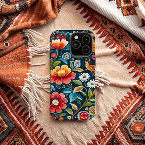 May include: A phone case with a colorful floral design. The case features a dark blue background with bright red, yellow, and orange flowers. There is a small bird with a yellow beak and a brown body on the case.