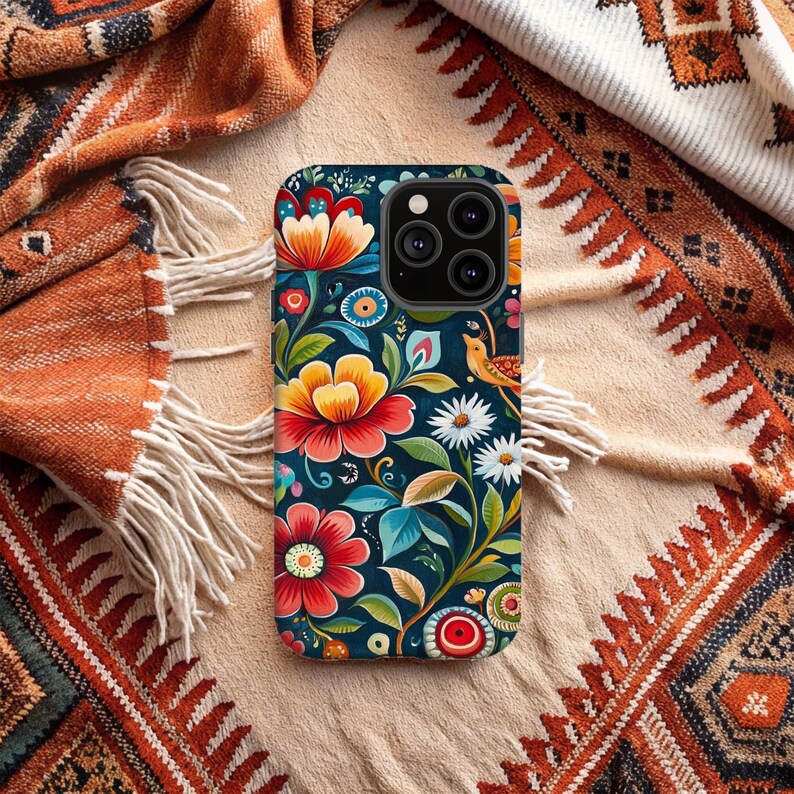 May include: A phone case with a colorful floral design. The case features a dark blue background with bright red, yellow, and orange flowers. There is a small bird with a yellow beak and a brown body on the case.