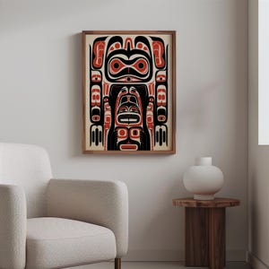 May include: A framed print of a Northwest Coast Indigenous art design featuring a stylized human figure with geometric patterns in black, red, and white.