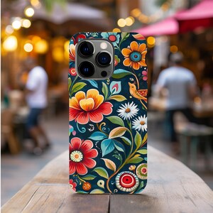 May include: A phone case with a colorful floral design. The case features a dark blue background with bright red, yellow, and green flowers. There is a small bird with a yellow body and red beak on the case.