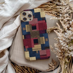 Könnte beinhalten: Eine rechteckige Smartphone-Hülle mit einem geometrischen Muster aus ineinandergreifenden Quadraten und Rechtecken in Marineblau, Dunkelrot, Bordeaux und mattem Gold. Die Hülle hat eine Aussparung für ein Dreifach-Kamerasystem oben links.