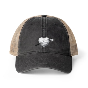 May include: A black and tan trucker hat with a golf-themed design. The design features a golf ball in the shape of a heart, pierced by a golf club. The hat has a curved brim and a mesh back.