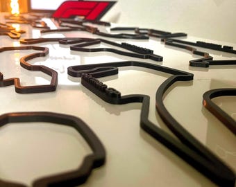May include: A collection of black 3D printed race track outlines, some with the name of the track printed on them.