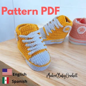 May include: A crochet pattern PDF for baby sneakers. The image displays two high-top sneakers, one mustard yellow and one peach, both featuring white laces, white toe caps, and a circular white side patch. The text Pattern PDF is visible.