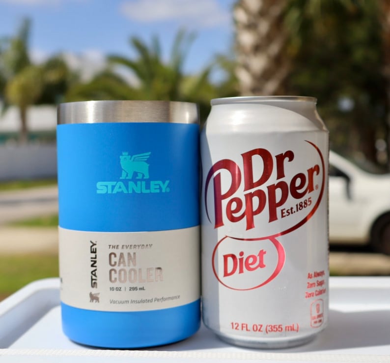 May include: A blue Stanley 10 ounce can cooler with the Stanley logo and the text "The Everyday Can Cooler" and a Diet Dr Pepper can with the text "Dr Pepper Diet Est. 1885" and "12 FL OZ (355 ml)".