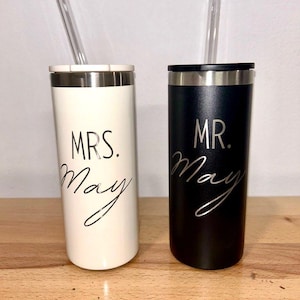 May include: Two stainless steel tumblers with lids and straws. One tumbler is white with black text that says "MRS. May" and the other tumbler is black with white text that says "MR. May".