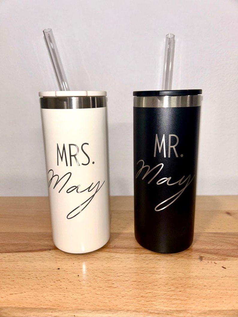 May include: Two stainless steel tumblers with lids and straws. One tumbler is white with black text that says "MRS. May" and the other tumbler is black with white text that says "MR. May".