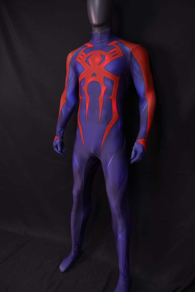 May include: A full-body costume in shades of blue and red, featuring a high collar and a prominent red spider emblem on the chest. The costume has red accents on the arms and a form-fitting design, suitable for cosplay or themed events.
