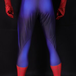 Puede incluir: Un disfraz de superh&eacute;roe azul y rojo. El disfraz tiene un cuerpo azul con detalles rojos en los guantes, las botas y la parte superior del pecho. Las secciones rojas tienen un patr&oacute;n de telara&ntilde;a.