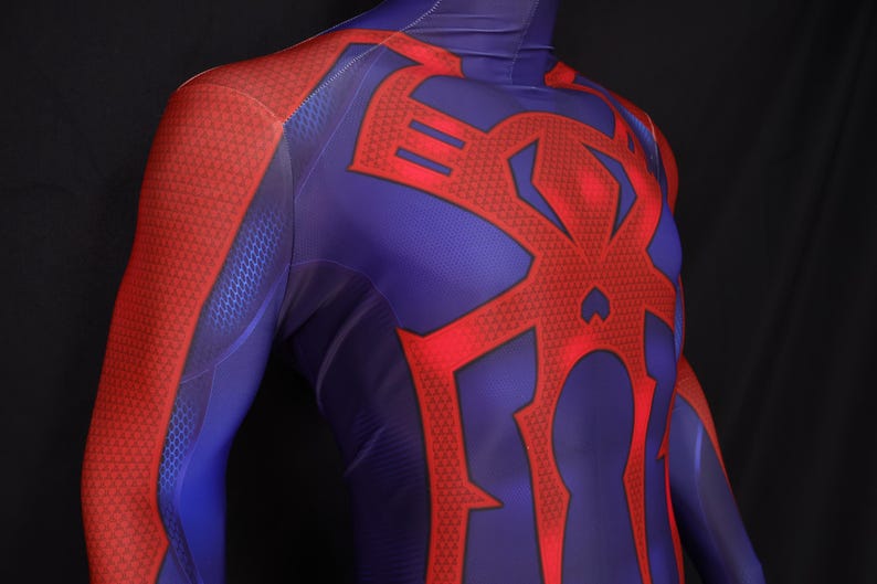 May include: A close-up of a blue and red bodysuit. The suit features a red spider emblem on the back and chest. The arms and shoulders are red with a textured pattern, while the torso is blue.