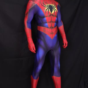 Puede incluir: Un disfraz de Spider-Man de cuerpo entero sobre un maniqu&iacute;. El disfraz es principalmente azul con detalles en rojo en los brazos, manos y piernas. Un gran emblema de ara&ntilde;a negra est&aacute; en el pecho.